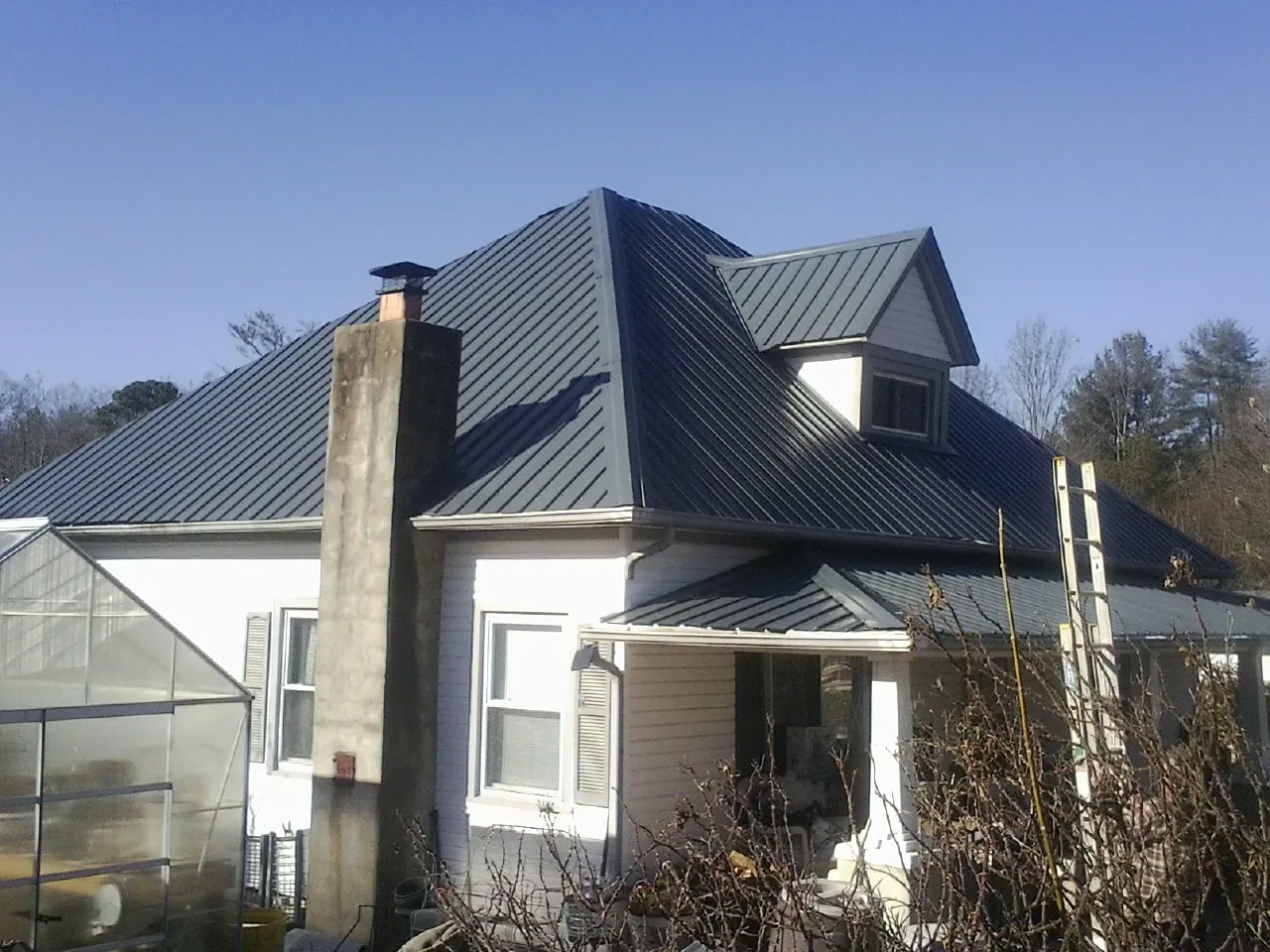 Dark blue standing seam metal roof on a white farmhouse with dormer — Slate & Tile Roof Repair by Roofing Brothers in Rochelle
