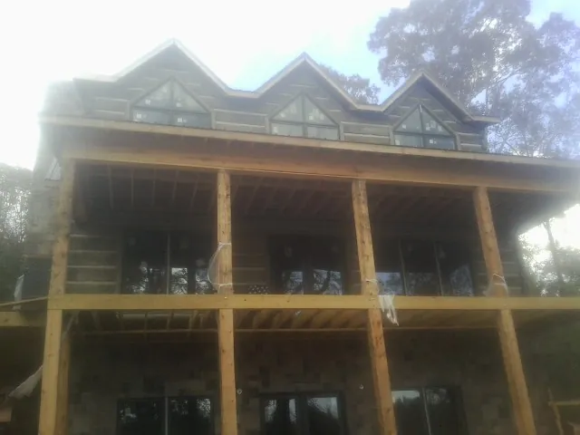 Dormers and porch framing on a large log home under construction — Roof Coating work by our crew in Rochelle