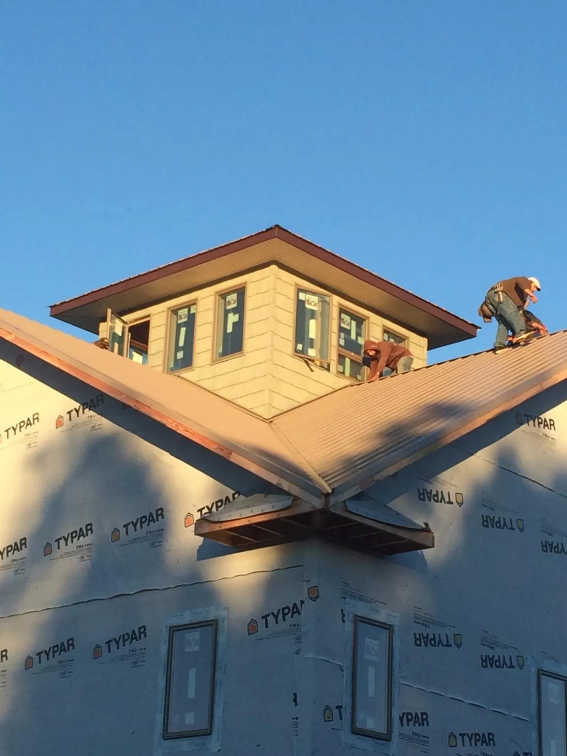 Roofers working around a rooftop cupola on a new metal roof at sunset — Roof Waterproofing in Rochelle by Roofing Brothers